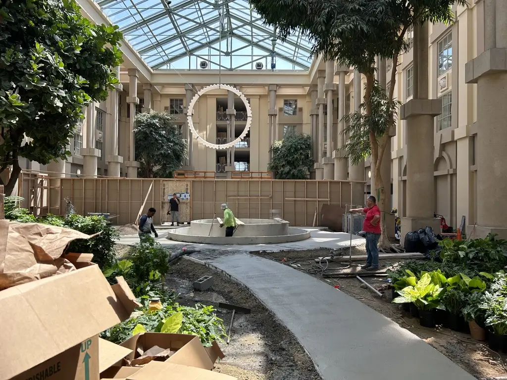 Workers are preparing the new walkway in the atrium area under a large glass ceiling at the Hyatt Regency Hotel.