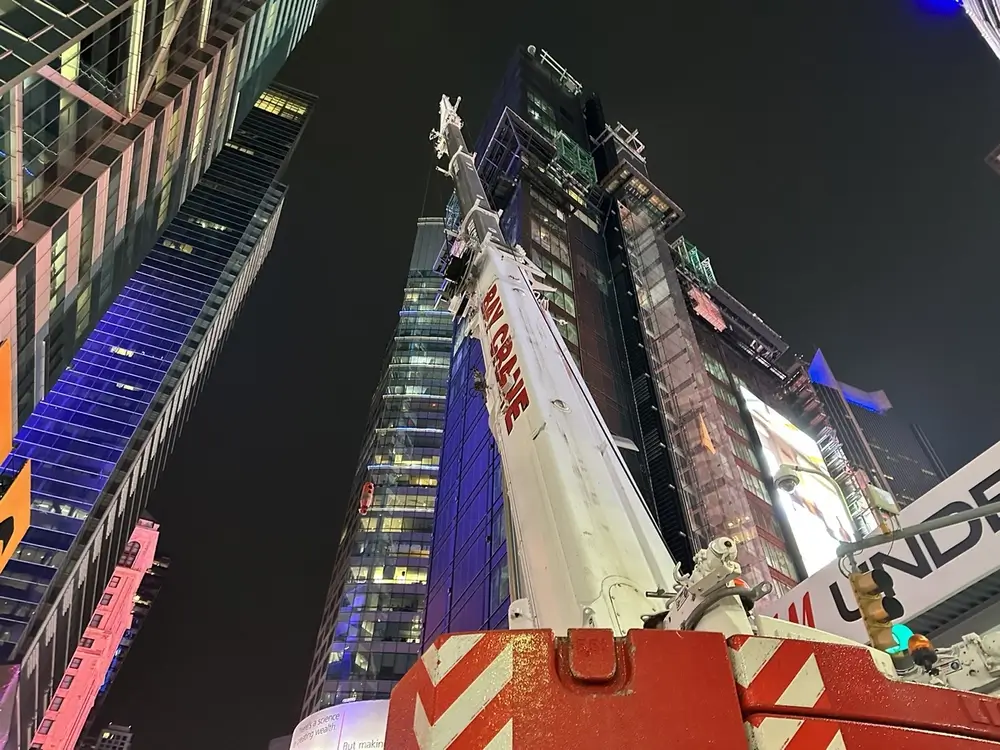 Close-up of a crane against the backdrop of skyscrapers at One Times Square, highlighting redevelopment progress.